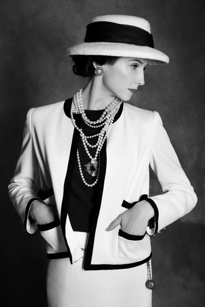 Black-and-white studio portrait of Svetlana Zakharova as Gabrielle Chanel, wearing a boater hat, layered pearls and a tailored jacket