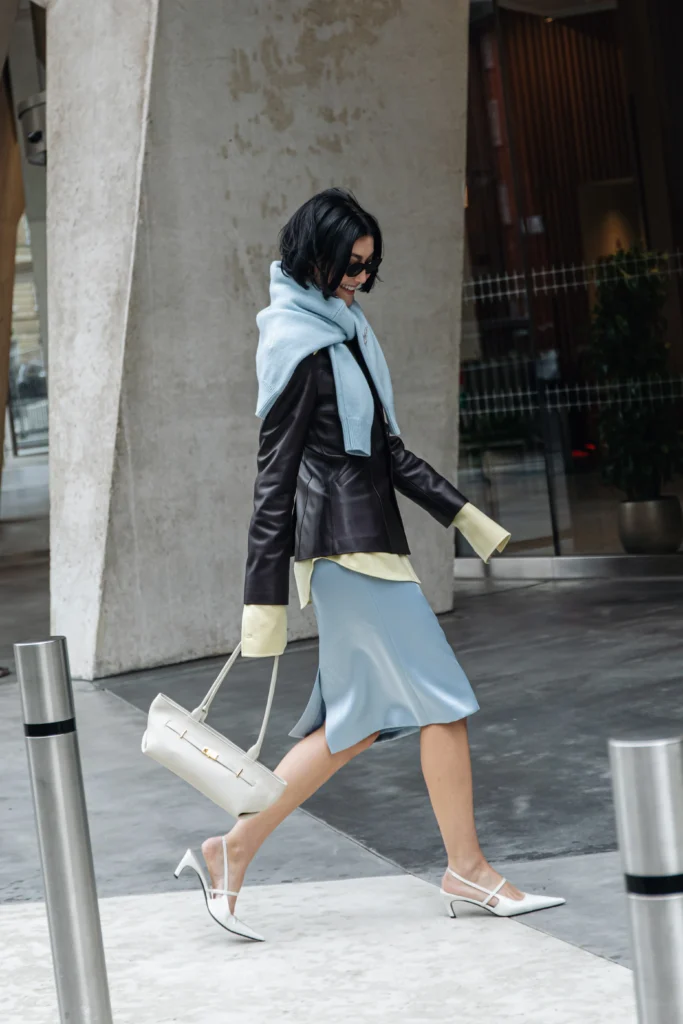Woman carrying a white east-west bag at London Fashion Week in February 2025